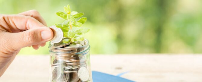Coins being added to jam jar with plant growing out